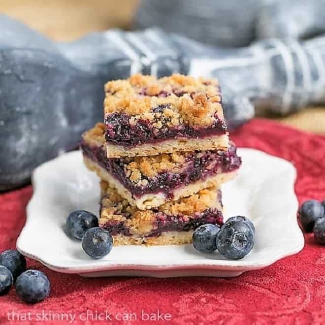 Blueberry Streusel Bars on a white plate with fresh blueberry garnish