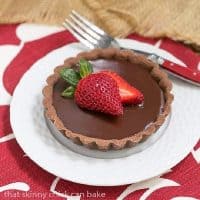 Double Chocolate Tartlet toped with a strawberry on a white plate