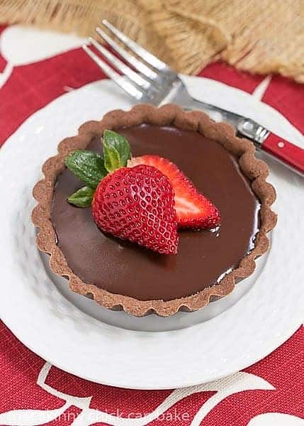 A Double Chocolate Tartlets on a white dessert plate with a red handled fork