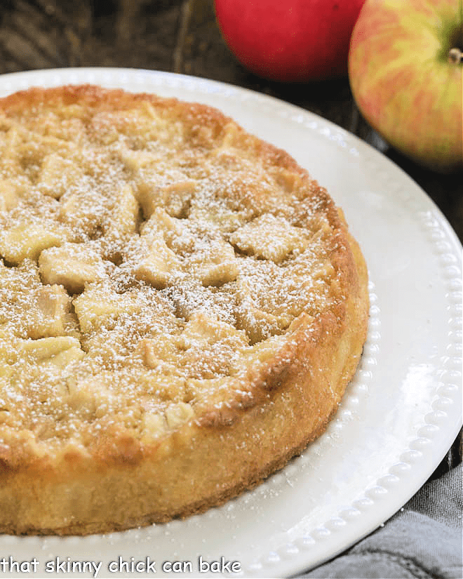 Uncut French Apple Cake on a white cake plate.