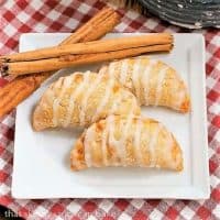 Fried Apple Pies on a white square plate with cinnamon sticks