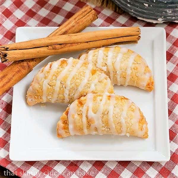 Fried Apple Pies on a white square plate with cinnamon sticks