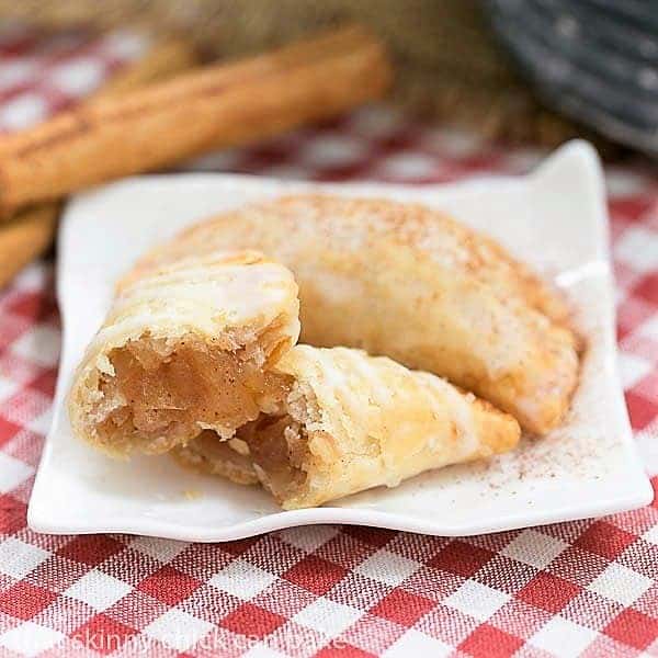 Two Fried Apple Pies on a ceramic plate, with one broken open to expose the filling