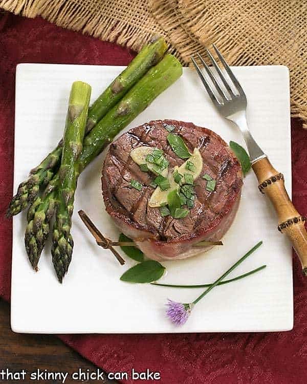 Overhead view of Grilled Tenderloin with Garlic Herb Butter on a square white plate.