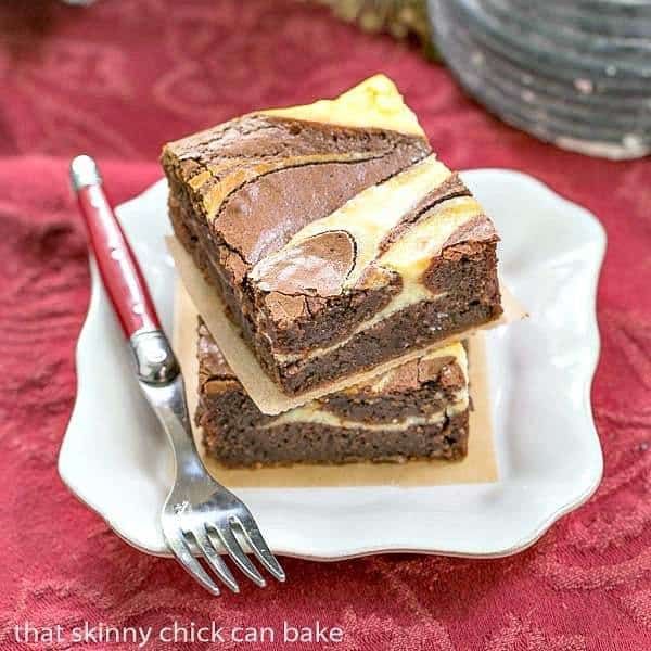 Ricotta Cheesecake Brownies stacked on a square white plate with a red handled fork.