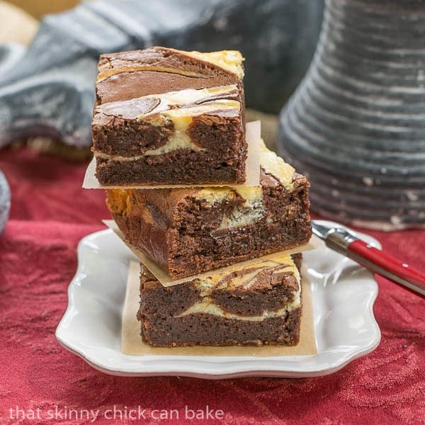 A stack of three Ricotta Cheesecake Brownies on a square white plate.