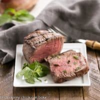 Grilled Steak with Garlic Butter and garnished with herbs on a square white plate