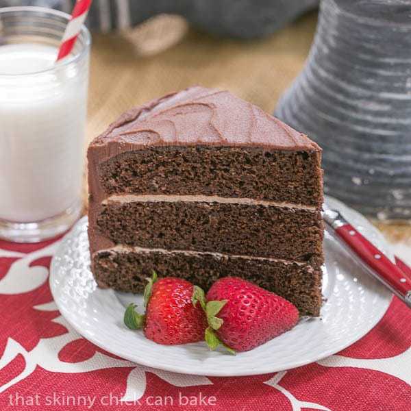 Slice of Chocolate Layer Cake with Vanilla Buttercream on a white plate with strawberries