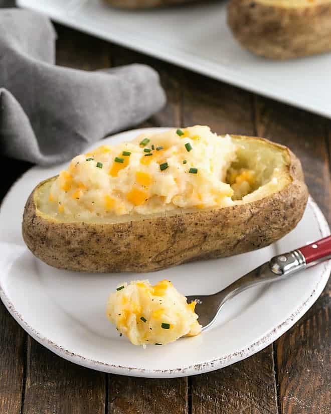 Easy Twice Baked Potatoes on a round white plate garnished with paprika and chives.