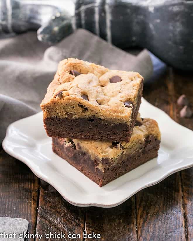 Brookies - An outrageously rich cookie bar with chocolate chip cookie dough baked over brownie batter! Two brookie bars stacked on a white plate.