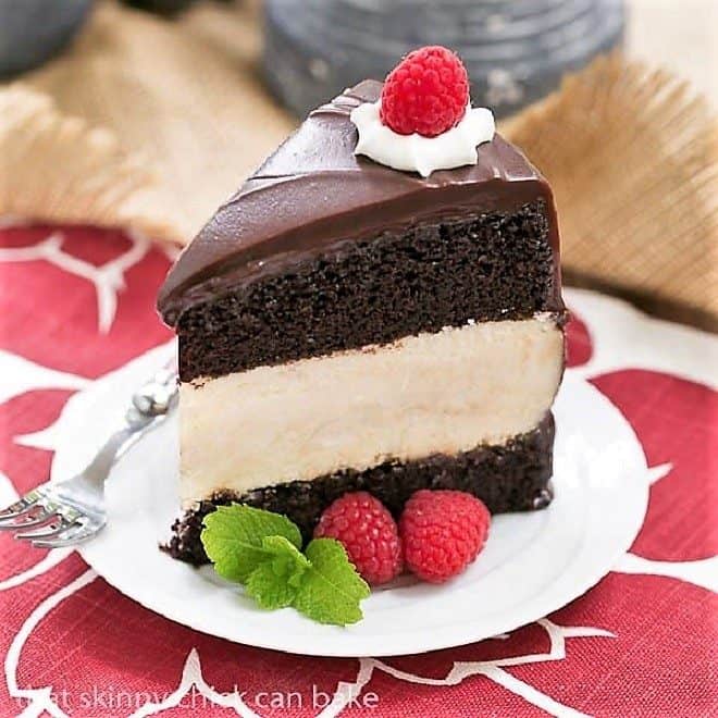 Slice of Cheesecake Filled Chocolate Cake on a white dessert plate