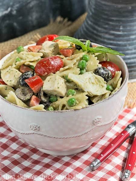 Pesto Pasta Salad in a white bowl with two red handled forks