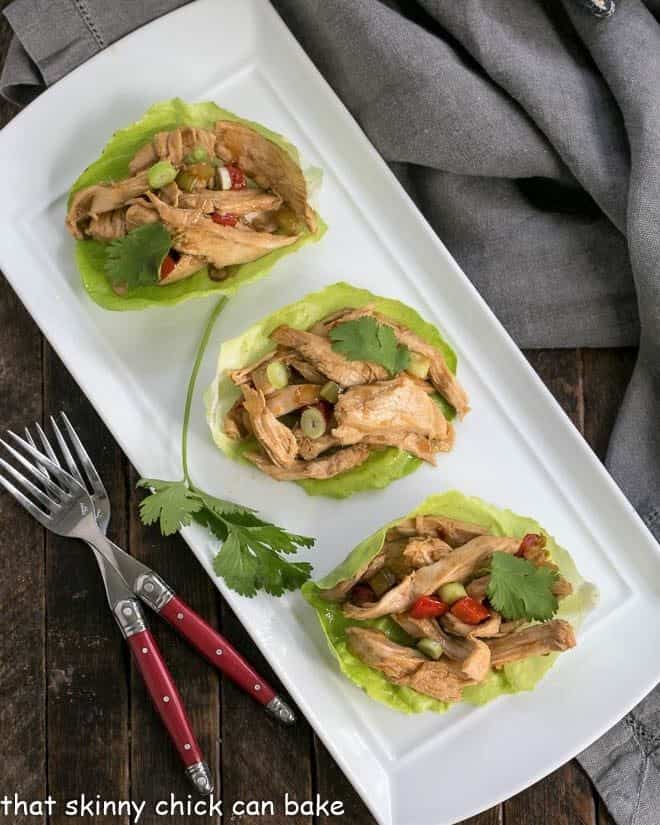 Overhead view of shredded chicken lettuce wraps on a white tray