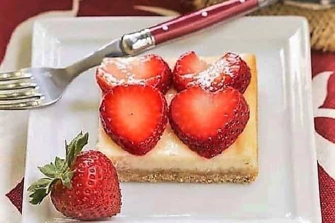 Strawberry Cheesecake Bars on a square plate with a red handled fork