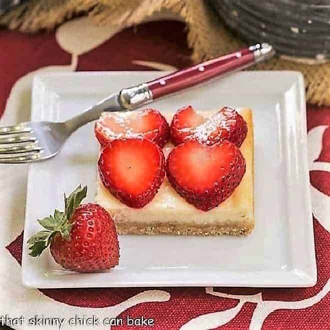 Strawberry Cheesecake Bars on a square plate with a red handled fork