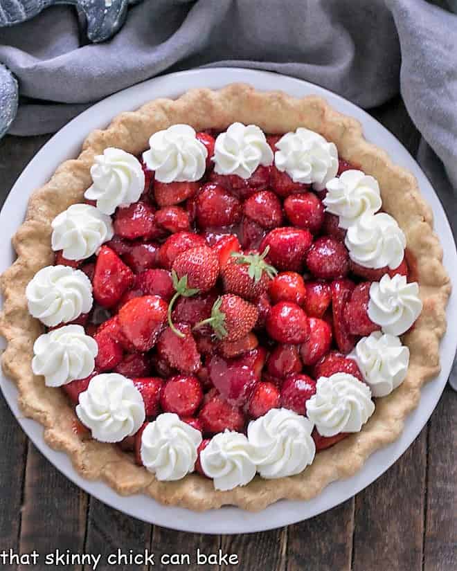 Overhead view of a fresh strawberry pie garnished with whipped cream