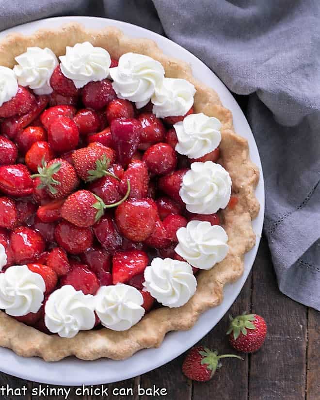 Partial overhead view of a strawberry pie with whipped cream garnishes