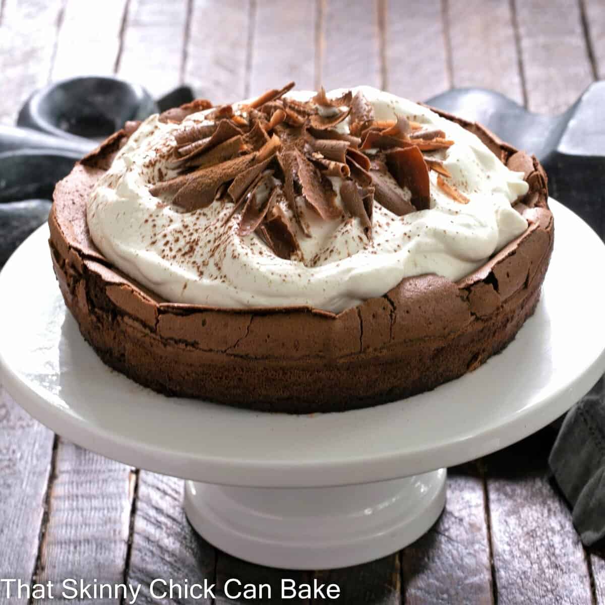 Chocolate souffle cake on a white ceramic cake stand.