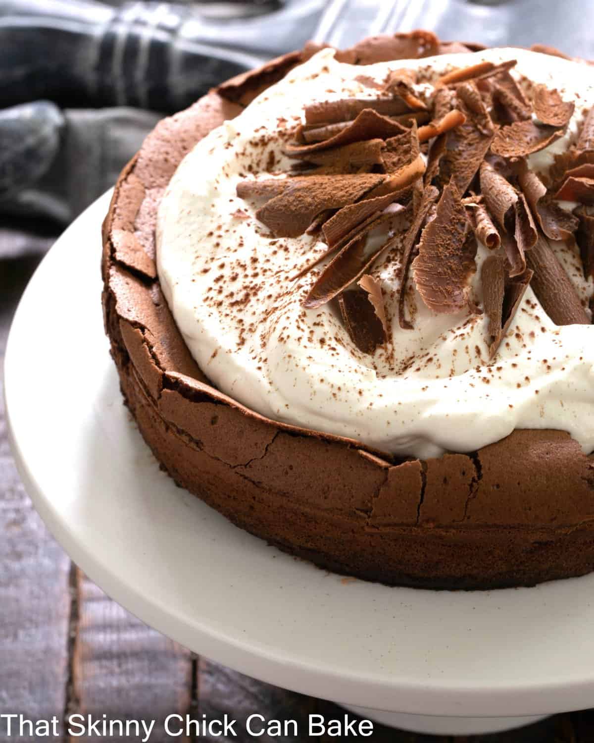 Left side of a Chocolate souffle cake on a white cake stand.