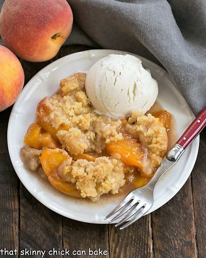 Overhead view of a Classic Peach Crisp on a white plate with a scoop of vanilla ice cream