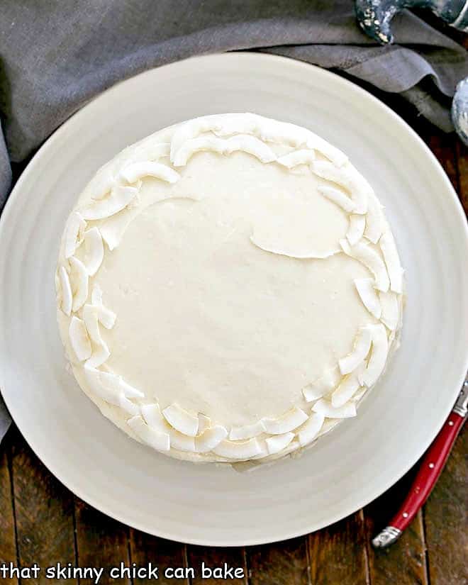 Overhead view of a Coconut Cake on a white cake plate.