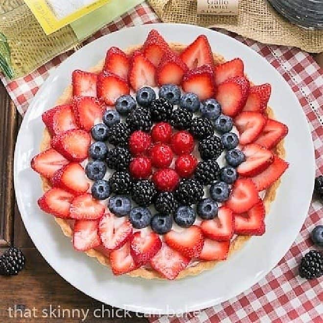 Summer Fruit Tart on a white plate with a bottle of white wine