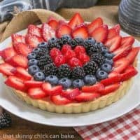 Summer fruit tart on a white plate set on a red and white napkin