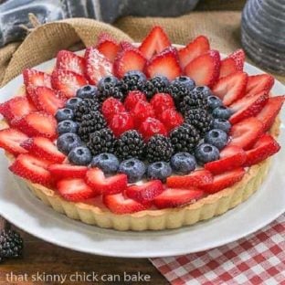 Summer fruit tart on a white plate set on a red and white napkin