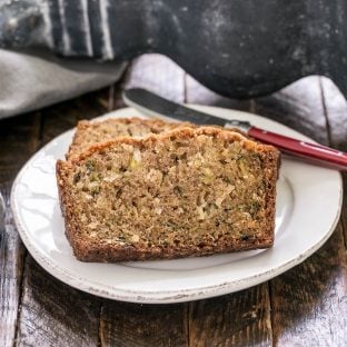 Sliced zucchini bread recipe on a white plate with a red handled knife