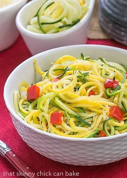 Zucchini Noodles with Parmesan in a white basket weave bowl with a red handle fork.