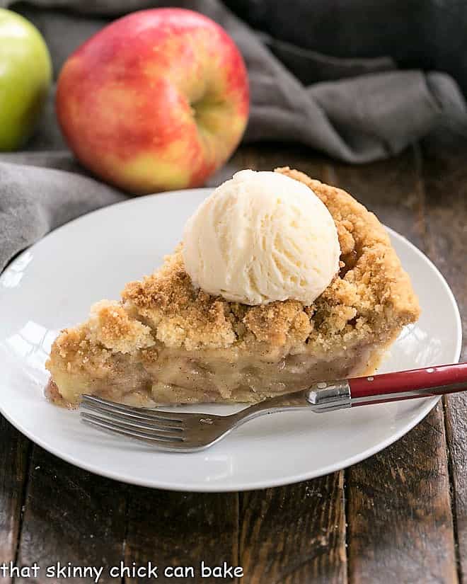 Slice of the best apple pie recipe topped with ice cream on a white plate