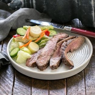 Slices of flank steak with a tossed salad on a whit