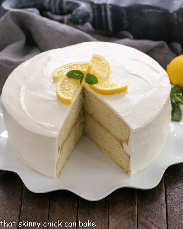 Lemon Cake with lemon curd filling on a white cake plate with a slice removed