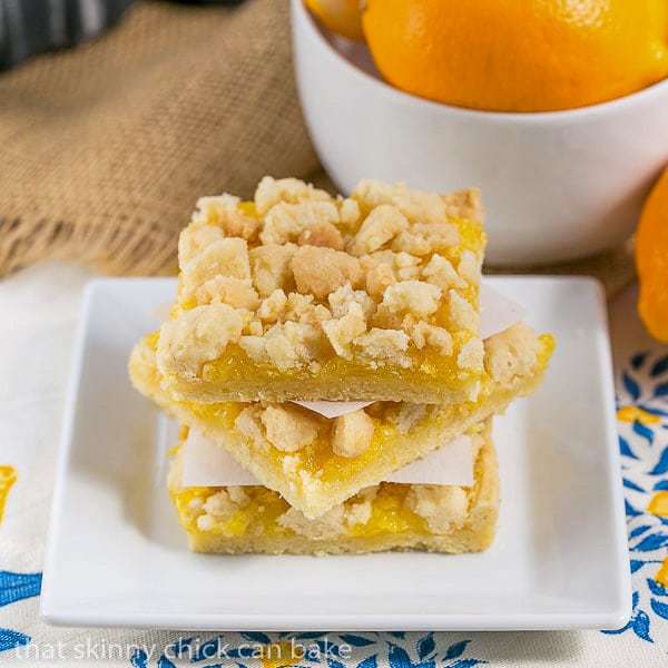 Meyer Lemon Streusel Bars - A scrumptious lemon bar with a sugar cookie crumble topping A stack of Meyer Lemon Streusel Bars on a square white plate.