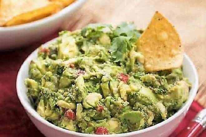 Mary's Classic Guacamole in a white ceramic bowl with a red handled serving spoon