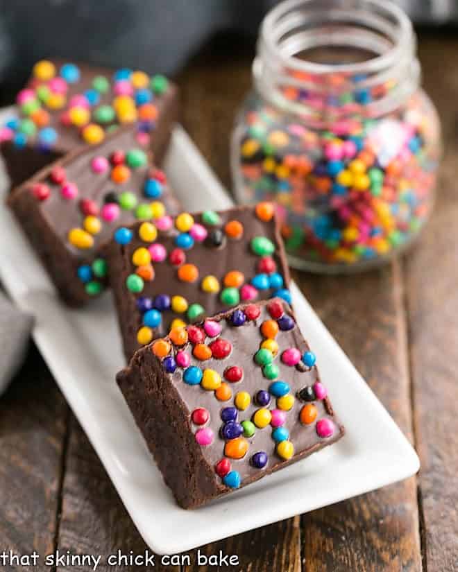 A tray of cosmic brownies with a jar of rainbow chip sprinkles.