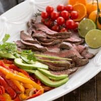 Flank Steak Fajitas and toppings on a white platter