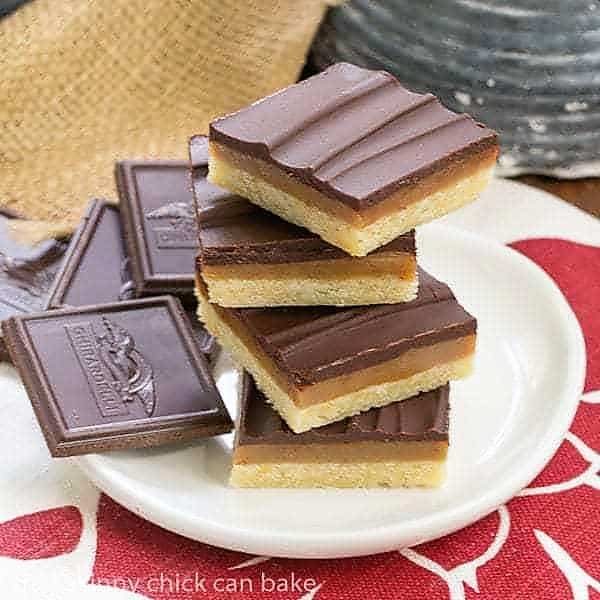 Ganache Topped Caramel Bars stacked on a round white plate