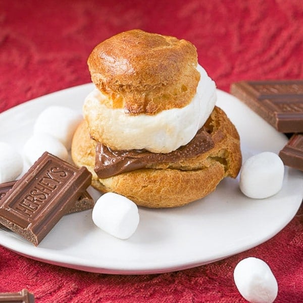 S'mores Cream Puffs on a white plate with chocolate and marshmallow garnishes