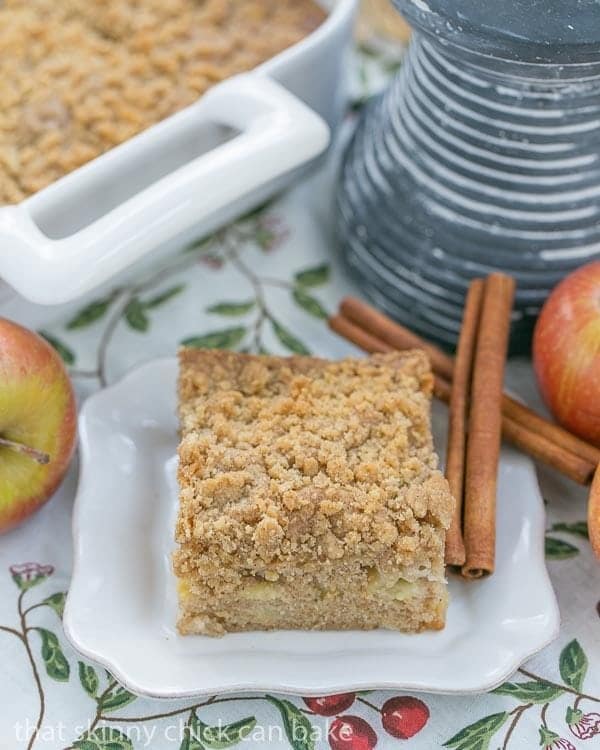 Apple Coffee Cake slice on a square white plate with cinnamon sticks