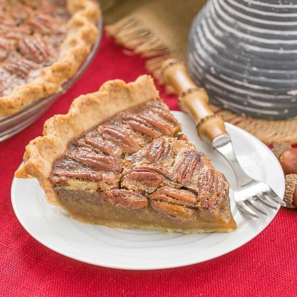 Classic Pecan Pie slice on a dessert plate over a red woven napkin.