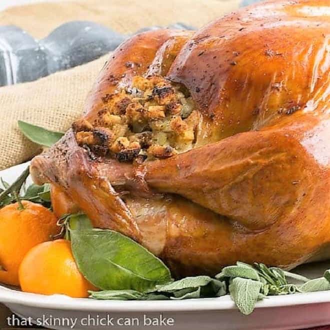 Dry Brined Turkey - the easiest way to brine your Thanksgiving bird and the BEST Turkey Recipe Dry Brined Turkey on a platter with herbs and oranges.