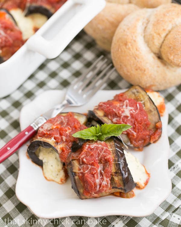 Eggplant Rollatini with Ricotta and Mozzarella on a square white plate garnished with fresh basil