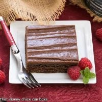 Chocolate Sheet Cake slice on a square white plate with raspberries