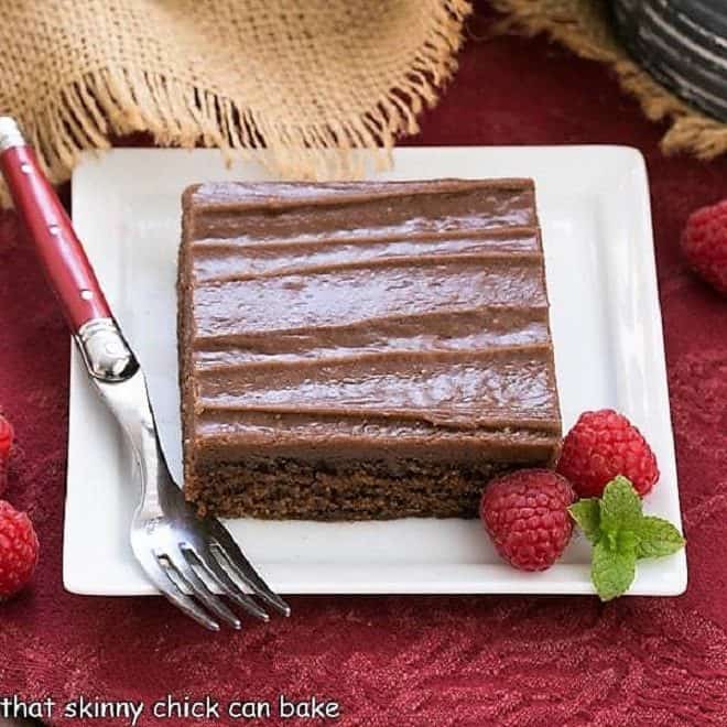 Chocolate Sheet Cake slice on a square white plate with raspberries