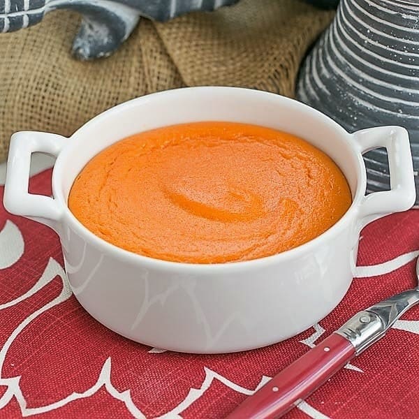 Carrot Puff in a round white baking dish with a red handled spoon.