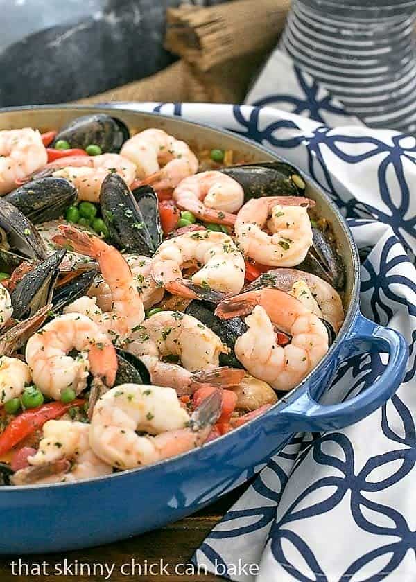 Julia Child's Paella a l'Americaine in a cast iron paella dish on a blue and white napkin