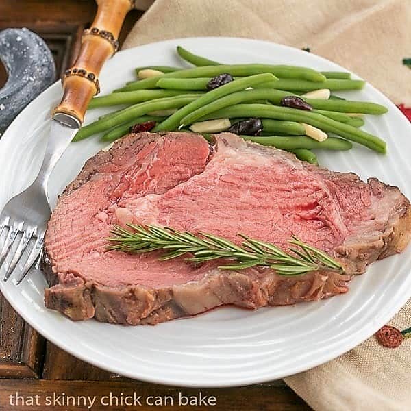 Slice of rare Classic Prime Rib on a white plate.