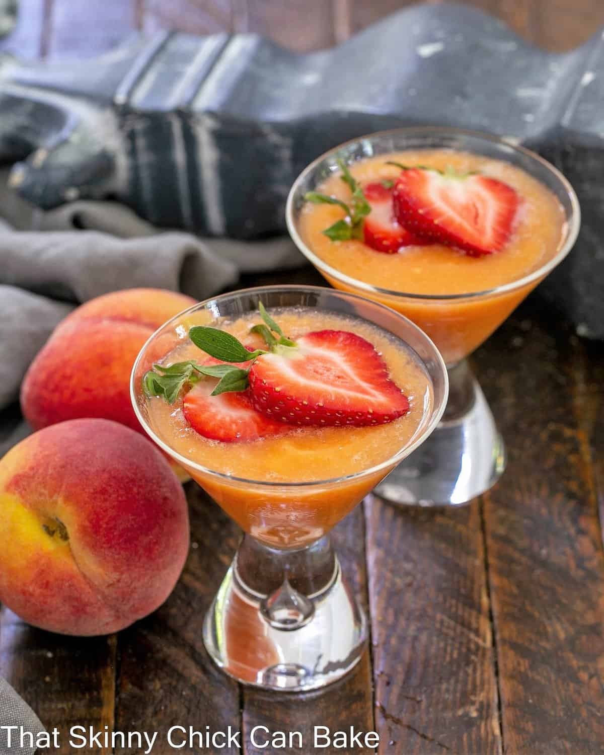 2 peach bellinis topped with strawberry slices.