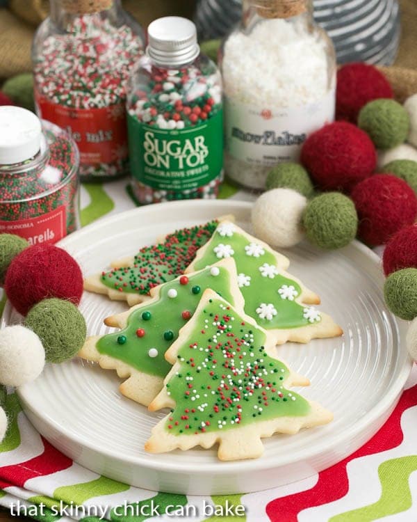 Easy Sugar Cookies with holiday frosting and sprinkles on a white plate.